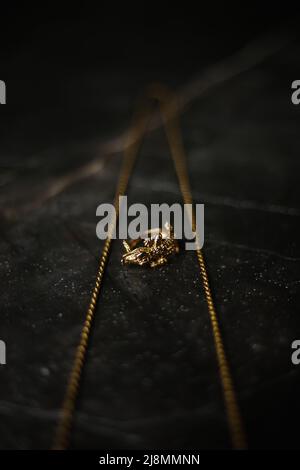 Anello d'oro a forma di coccodrillo con catena d'oro su sfondo di marmo scuro Foto Stock