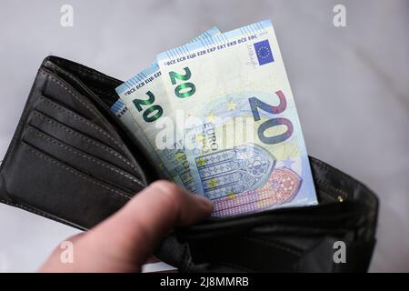 Prende o mette 20 euro bollette in un portafoglio su uno sfondo chiaro Foto Stock