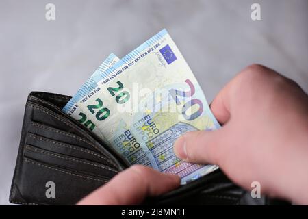 Prende o mette 20 euro bollette in un portafoglio su uno sfondo chiaro Foto Stock