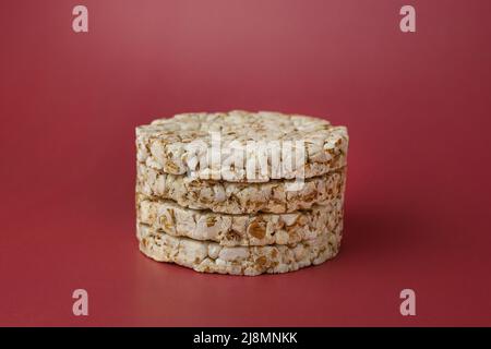 Riso grano saraceno croccante su uno sfondo isolato di colore Bordeaux (rosso-borgogna) primo piano Foto Stock