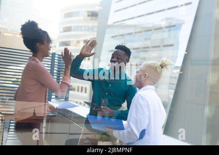 Albino afroamericano medio uomo d'affari adulto che guarda i colleghi afroamericani che fanno alto-cinque Foto Stock