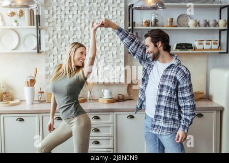 Soddisfatto uomo europeo millenario con stoppia e bionda signora godere del tempo libero, divertirsi e ballare Foto Stock