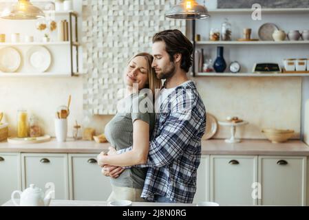 Allegro felice caucasico fascia millenaria con capezzoli biondo moglie, godere momento tenero in cucina leggera Foto Stock