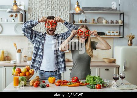 Soddisfatto divertente ragazzo caucasico millennial con stoppia e bionda femmina hanno divertimento, applicare pezzi di pepe agli occhi Foto Stock