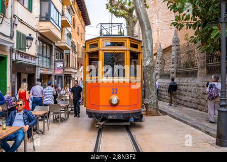 Tram arancione che si muove sulle piste ferroviarie tra edifici in città durante l'estate Foto Stock