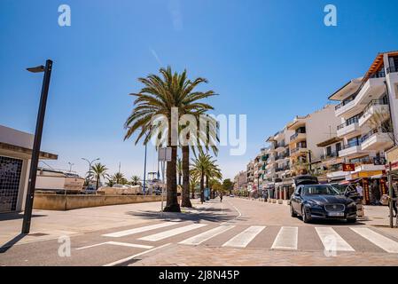 Auto parcheggiata su strada tra palme ed edifici in città contro il cielo blu Foto Stock