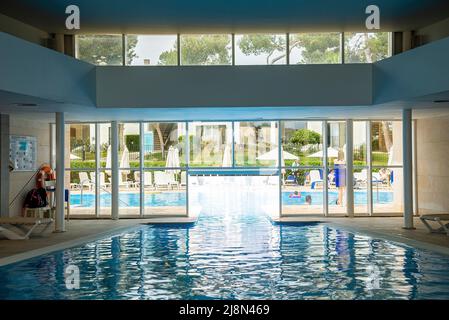 L'interno della piscina e' circondato da sedie a sdraio in un lussuoso resort Foto Stock