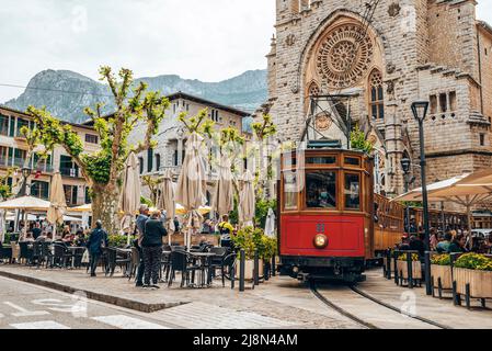 I turisti visitano mentre il tram si muove sulle rotaie contro la chiesa in città Foto Stock