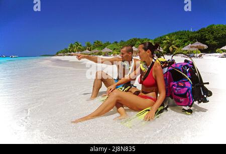Coppia con attrezzatura subacquea seduta sulla spiaggia dell'isola delle maldive Reethi Beach, Baa-Atoll, Maldive, Oceano Indiano, Asia Foto Stock