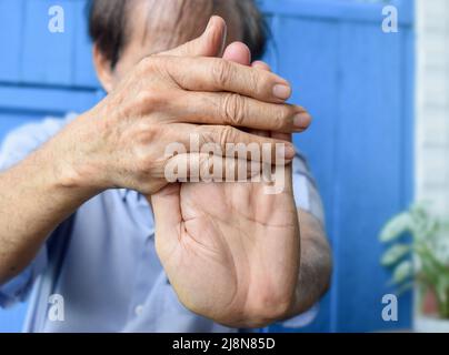 Rafforzamento dell'esercizio per i muscoli del braccio di un paziente maschile anziano asiatico con spasmo muscolare. Foto Stock