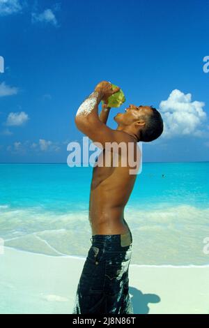 Uomo delle Maldive che beve acqua di cocco, spiaggia di una piccola isola inabitata, Atollo Laviyani, Maldive, Oceano Indiano, Asia Foto Stock
