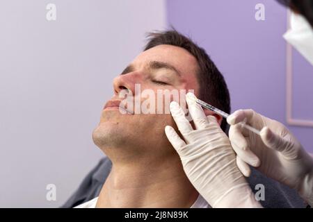 Il paziente si è rilassato durante un trattamento di ringiovanimento con iniezione di botox Foto Stock