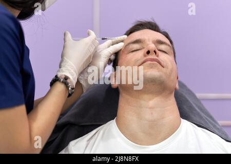 Paziente rilassato che ottiene un'iniezione botox per il trattamento di ringiovanimento facciale Foto Stock