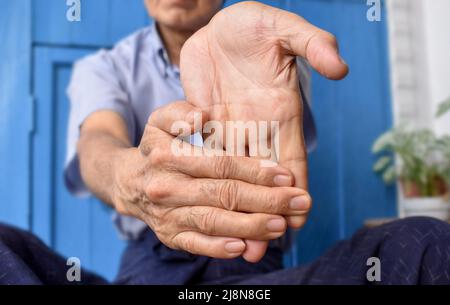 Rafforzamento dell'esercizio per i muscoli del braccio di un paziente maschile anziano asiatico con spasmo muscolare. Foto Stock