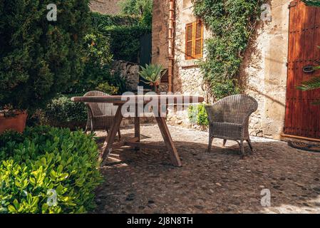 Tavolo e sedie disposti fuori casa contro piante in città Foto Stock