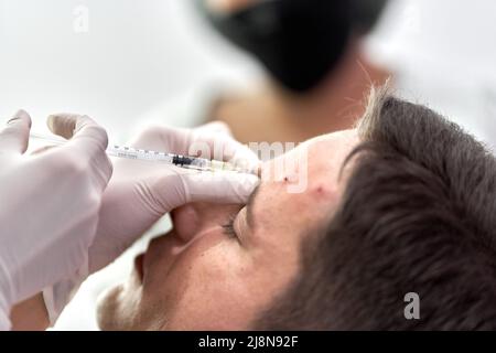 Concentrarsi su un'iniezione botox che entra nella pelle della fronte di un paziente Foto Stock