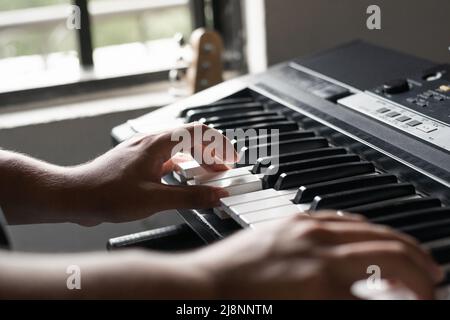 dettaglio delle mani di un uomo latino nel suo studio di musica che compone canzoni su un sintetizzatore o piano elettrico. ragazzo che combina nuovi suoni per la sua artis Foto Stock