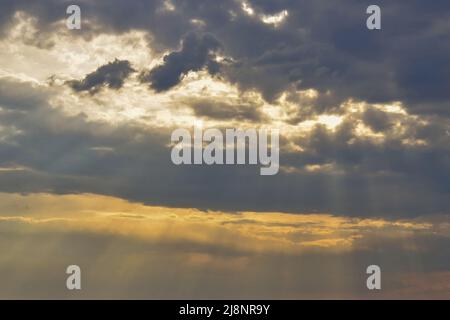 La luce del sole si rompe attraverso le nuvole di tempesta. Cielo nuvoloso al tramonto. Cielo e nuvole sfondo. Foto Stock