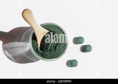 additivi naturali e superfood. polvere di alghe spirulina verde in ciotola di vetro e pillole su sfondo bianco. concetto di stile di vita sano. cibo biologico Foto Stock