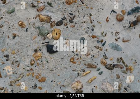 Texture di calcestruzzo con ciottoli multicolore sulla superficie. Muro monolitico in calcestruzzo o percorso da giardino con inclusione di ciottoli multicolore. Foto Stock