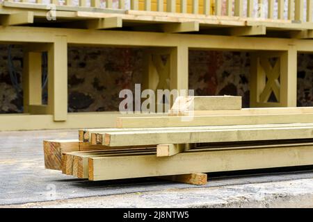 Pila di legno impregnato assi e travi di fronte ad un terrazzo di legno non finito Foto Stock