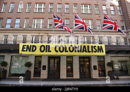 Gli attivisti hanno svelato una bandiera con slogan che recita fine colonialismo petrolifero. Estinzione attivisti della ribellione tempesta maggio Fair hotel nel centro di Londra in protesta di un vertice del petrolio (Africa Energies Summit) che si sta svolgendo in questo hotel a cinque stelle. Foto Stock