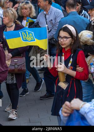 Sofia, Bulgaria - 09 maggio 2022: Una ragazza adolescente negli specticle detiene bandiera Ucraina, in piedi nella folla Foto Stock