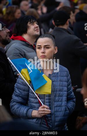 Sofia, Bulgaria - 28 aprile 2022: Una giovane donna con un aspetto pensivo è in piedi in una folla con bandiera Ucraina Foto Stock