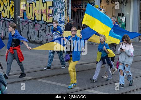 Sofia, Bulgaria - 09 maggio 2022: Una famiglia - madre, padre e i loro figli adolescenti camminano insieme, tenendo insieme il grande banner ucraino Foto Stock