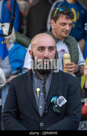 Un uomo audace ed elegante con un bearded nero intrecciato, vestito in vestito, sta nella folla Foto Stock