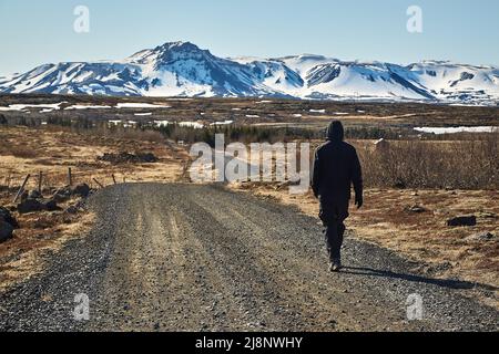 Uomo che cammina su strada di ghiaia in Islanda Foto Stock