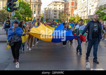 Una colonna di maschi e femmine cammina con una bandiera gigante dell'Ucraina nelle loro mani alla dimostrazione pro-Ucraina sostegno Ucraina Foto Stock