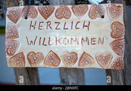 Il segno autofarato con la scritta 'Herzlich willkommen' in lingua tedesca si traduce in 'heartly welcome' in inglese Foto Stock