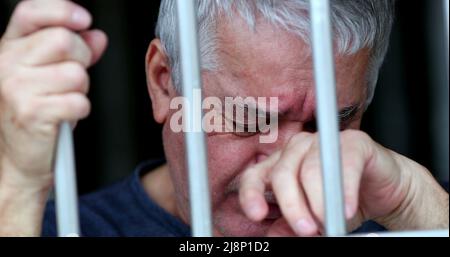Uomo anziano imprigionato dietro sbarre che piangeva. Persona anziana che soffre Foto Stock