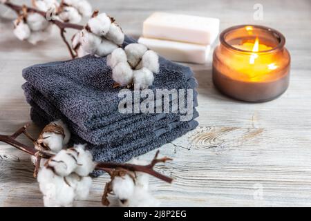 Quattro salviette grigie per il viso, due saponi, una candela in un vaso di vetro e un ramo di cotone presso il centro benessere. Salone di bellezza. Comfort e cura Foto Stock