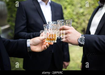 Lo sposo e gli ospiti si abbordano i vetri al matrimonio. Foto Stock