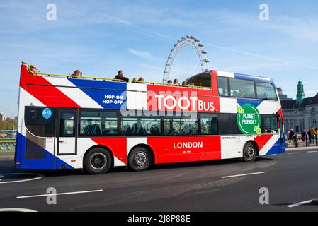 Toot Bus, London tour bus in Union Jack bandiera autobus colorato su Westminster Bridge Road, Londra, Regno Unito con London Eye. Gita turistica della Bath Bus Company Foto Stock