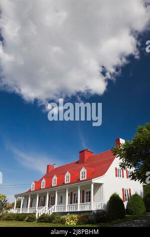 Vecchia casa in stile cottage Canadiana del 1825 circa con rivestimento in legno bianco e tetto in legno di cedro dipinto di rosso. Foto Stock