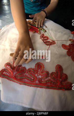 Una donna che unisce motivi decorativi su tessuti utilizzando lo strumento tradizionale a Sawahlunto, West Sumatra, Indonesia. Foto Stock