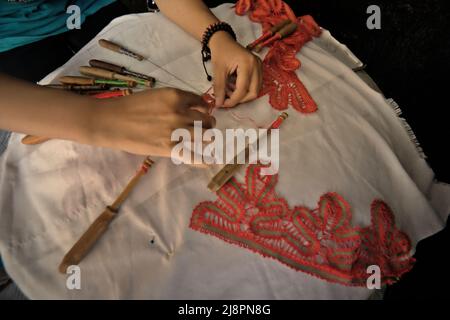 Una donna che unisce motivi decorativi su tessuti utilizzando lo strumento tradizionale a Sawahlunto, West Sumatra, Indonesia. Foto Stock