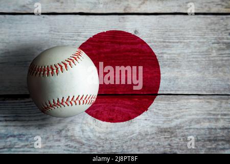 Baseball in pelle su sfondo rustico in legno dipinto con bandiera giapponese con spazio copia. Il Giappone è una delle nazioni di baseball più importanti del mondo. Foto Stock