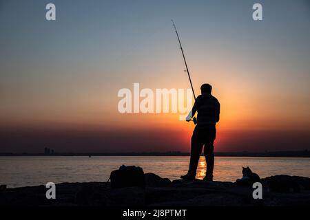 Istanbul, Turchia. 17th maggio 2022. Una silhouette di un uomo visto la pesca al tramonto. Un uomo che pesca al tramonto sulle rocce è stato visto sulla spiaggia Moda nel distretto di Kadikoy di Istanbul. Credit: SOPA Images Limited/Alamy Live News Foto Stock
