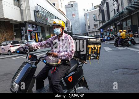 Un corriere che indossa una maschera per il viso e un casco fornisce cibo su una bicicletta elettrica. Secondo l'economia cinese dovrebbe vedere un miglioramento questo mese, nonostante i deboli dati aziendali in aprile, e le attività economiche potrebbero rimbalzo con una graduale ripresa della spesa delle famiglie e un forte sostegno agli investimenti fissi nei mesi successivi, funzionari ed esperti hanno detto lunedì. Essi hanno affermato che l'economia cinese dovrebbe gradualmente stabilizzarsi e riprendersi, con un miglioramento di alcuni indicatori economici chiave, un migliore contenimento dei focolai di COVID-19 e un maggiore sostegno politico. Foto Stock