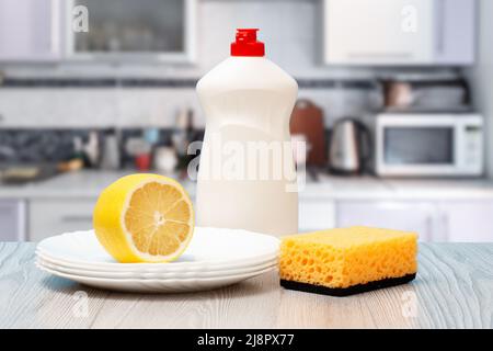 Bottiglia di plastica di liquido per lavastoviglie, piatti puliti, limone e spugna in cucina. Concetto di lavaggio e pulizia. Foto Stock