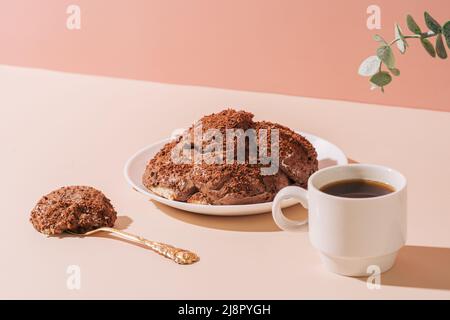 Un pezzo di torta sulla piastra accanto alla tazza di caffè su sfondo rosa Foto Stock