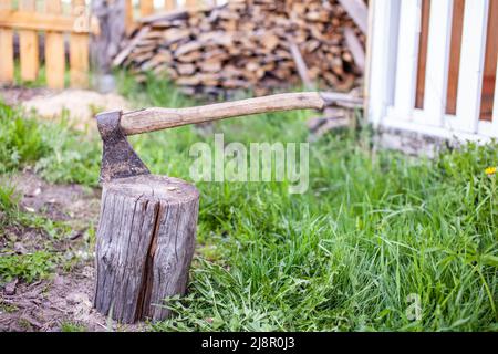 Vita di villaggio. Un'ascia in un ceppo o ceppo per tritare legna da ardere. Il tritatutto in legno si stacca in canapa di legno. Deforestazione da un'ascia affilata. Arrugginito ma molto Foto Stock