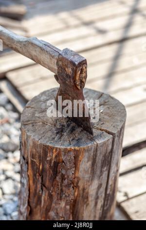 Vita di villaggio. Un'ascia in un ceppo o ceppo per tritare legna da ardere. Il tritatutto in legno si stacca in canapa di legno. Deforestazione da un'ascia affilata. Arrugginito ma molto Foto Stock