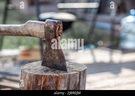 Vita di villaggio. Un'ascia in un ceppo o ceppo per tritare legna da ardere. Il tritatutto in legno si stacca in canapa di legno. Deforestazione da un'ascia affilata. Arrugginito ma molto Foto Stock