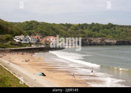 La gente gode del sole primaverile sulla spiaggia a Sandsend, North Yorkshire, Inghilterra, Regno Unito Foto Stock