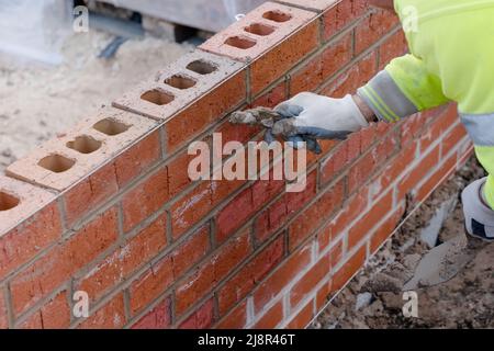 Muratore che riempie le giunzioni nella parete di mattone. Giunti di puntamento nella parete di mattone Foto Stock